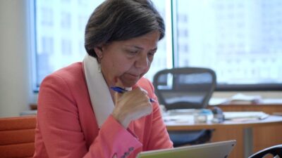 Dr. Sandra Hernandez sitting at desk reading on iPad.