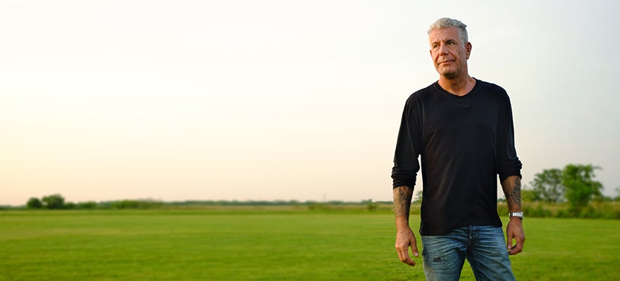 Anthony Bourdain standing in a field.