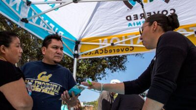 Ana Oliva, left, and Felix Portillo of Los Angeles get insurance information from Valeria Lopez at a Covered California event. Ricardo DeAratanha / Los Angeles Times