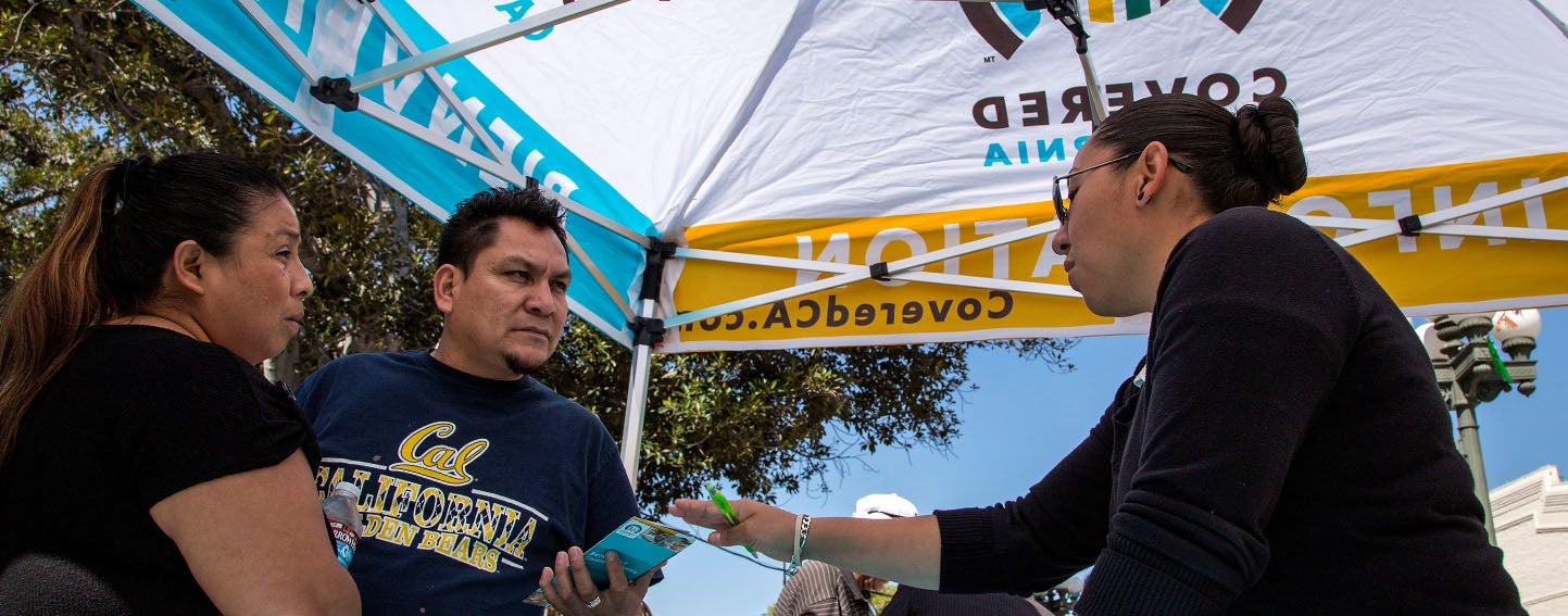 Ana Oliva, left, and Felix Portillo of Los Angeles get insurance information from Valeria Lopez at a Covered California event. Ricardo DeAratanha / Los Angeles Times