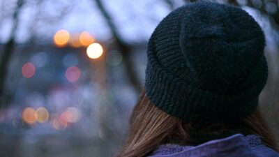 Young girl in knit hat looking into distance at dusk.