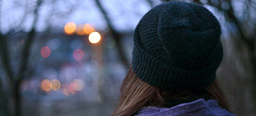 Young girl in knit hat looking into distance at dusk.
