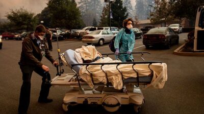 Medical personnel evacuate patients as the Feather River Hospital burns while the Camp Fire rages through Paradise, Calif., on Thursday, Nov. 8, 2018. Tens of thousands of people fled a fast-moving wildfire Thursday in Northern California, some clutching babies and pets as they abandoned vehicles and struck out on foot ahead of the flames that forced the evacuation of an entire town. (AP Photo/Noah Berger)