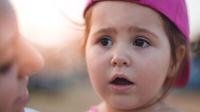 Small girl being held by her mother,looking concerned.