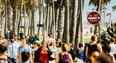 Crowd of people walking along beach path in Southern California.