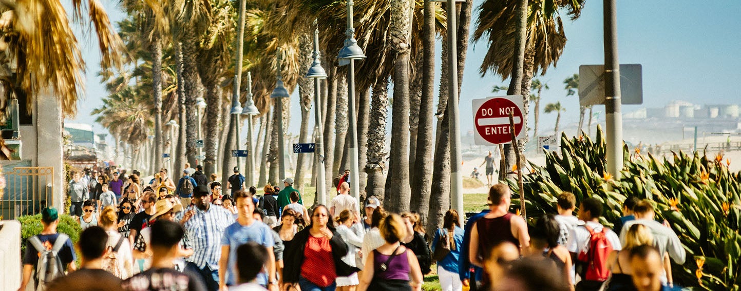 Crowd of people walking along beach path in Southern California.