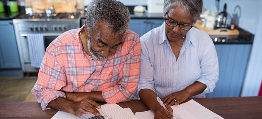Older couple reviewing their finaces together at a kitchen table.