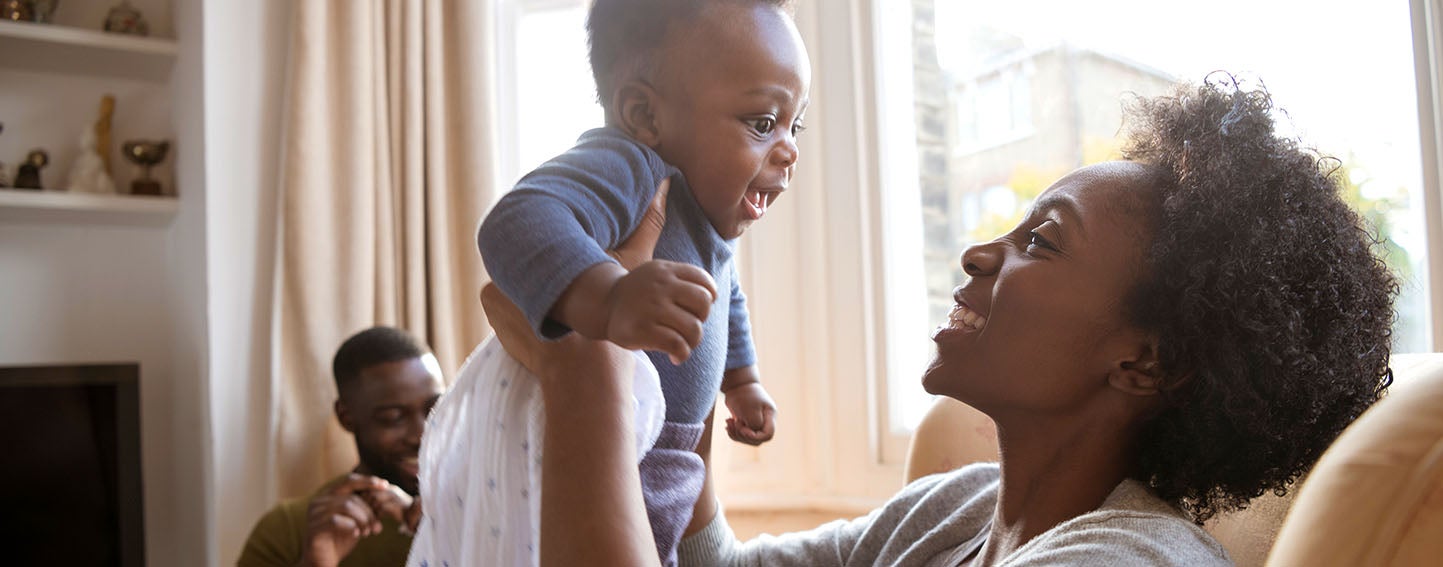 happy family with new baby sits in living room