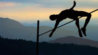 Silouette of pole vaulter clearing the pole.