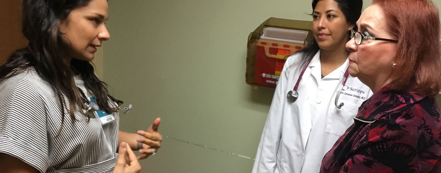 Dr. Karla Garcia, PRIME-LC graduate and attending family physician at San Ysidro Health in Chula Vista, a border city, talks to patient Gloria Lamadrid de Santana at a wellness visit, while first year resident Dr. Alondra Cardenas looks on. Garcia oversees and trains resident doctors, discussing their cases with them, and also has her own patients.