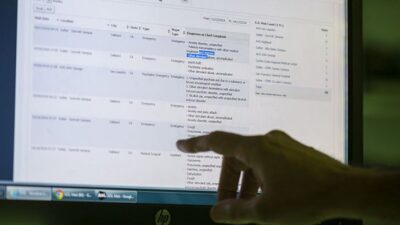 Hand points at computer monitor displaying electronic health records