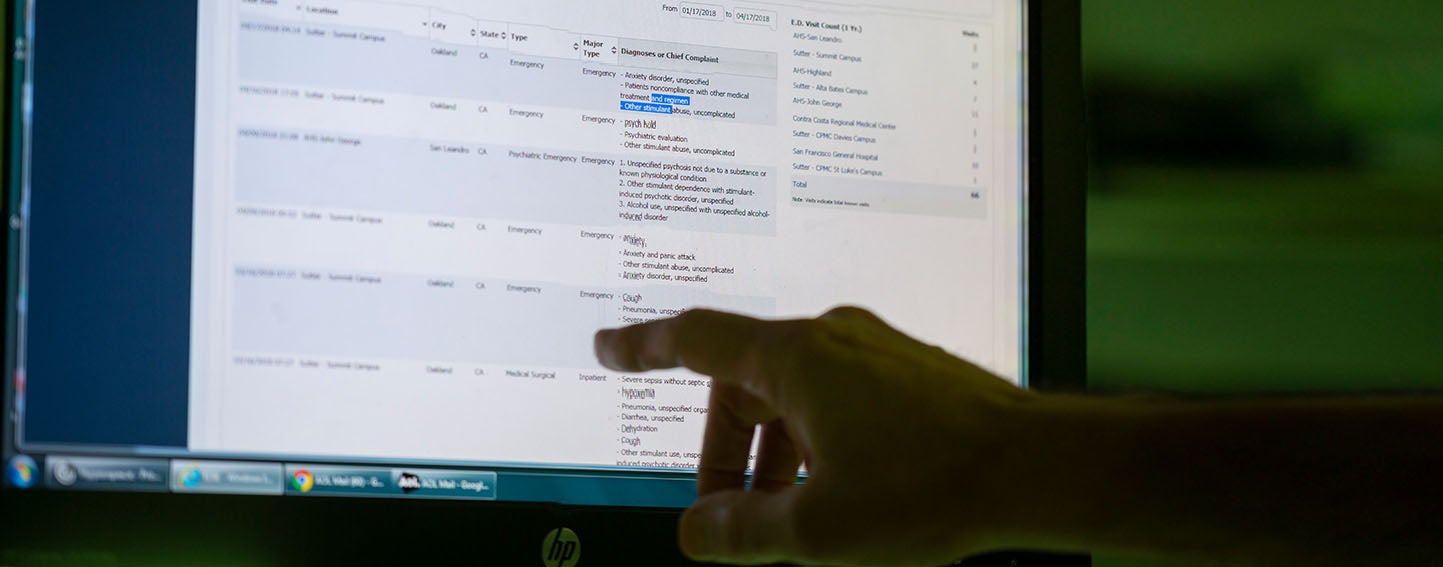 Hand points at computer monitor displaying electronic health records