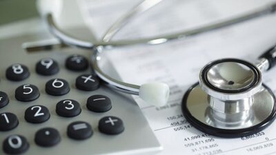 medical bill with a stethoscope and calculator sitting on top of it