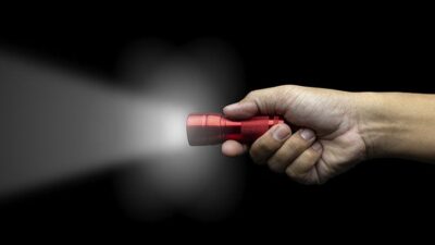hand holding red flashlight against a black background