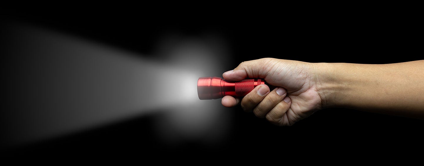 hand holding red flashlight against a black background