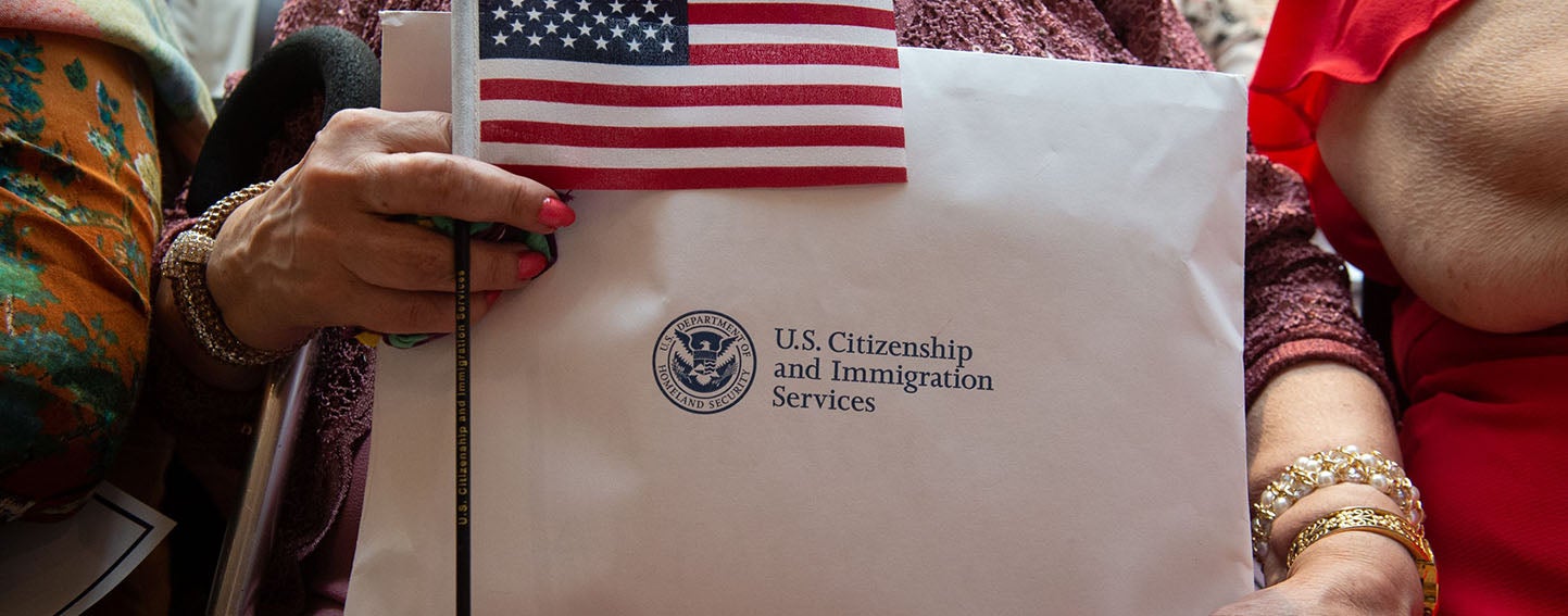 new citizen holds citizenship documents and a flag