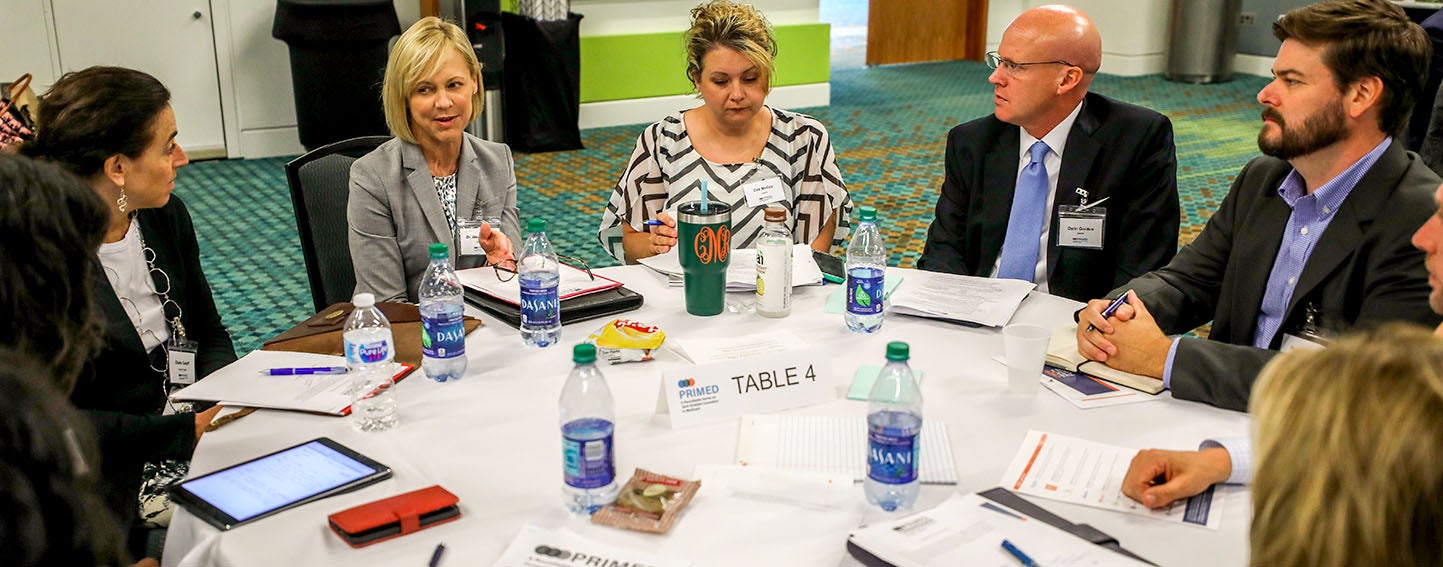 People sitting around a table at a conference, having a discussion