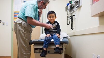 Young client is seen by medical practitioner at La Clinica, Oakland, CA.