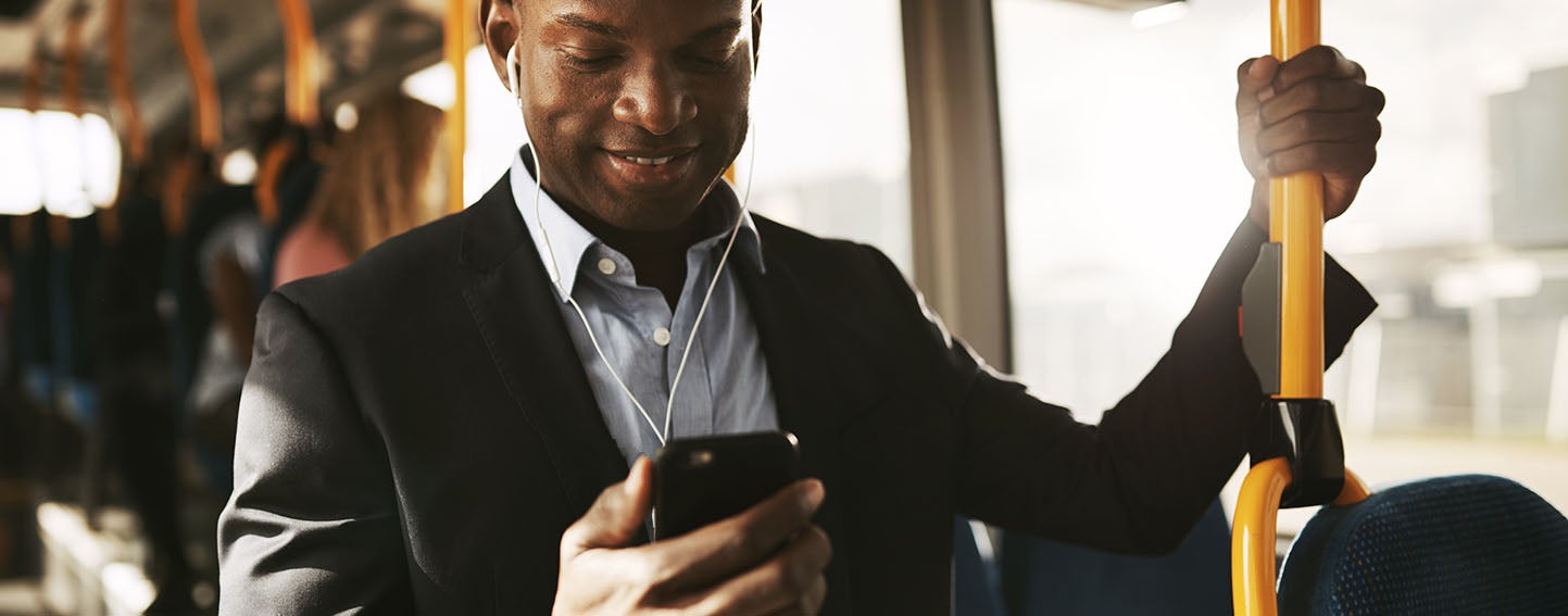 Man riding transit listening to a program on his smartphone with headphones