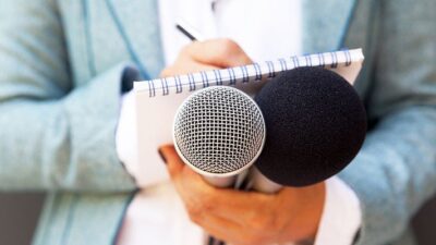 journalist takes notes while holding microphones