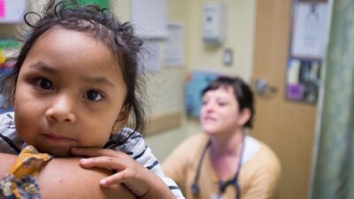 Mother and baby at clinic with doctor. Baby is looking directly into the camera.