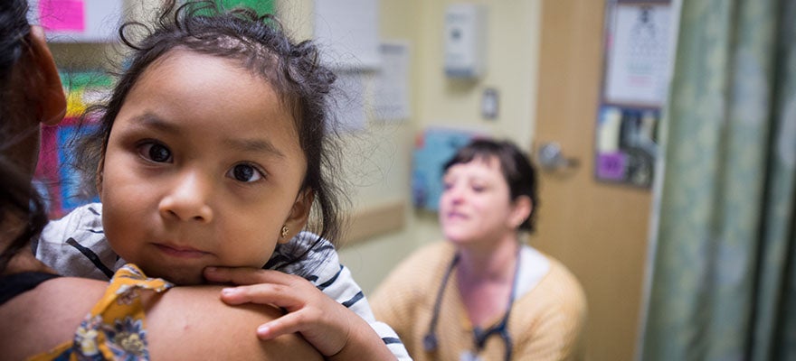 Mother and baby at clinic with doctor. Baby is looking directly into the camera.