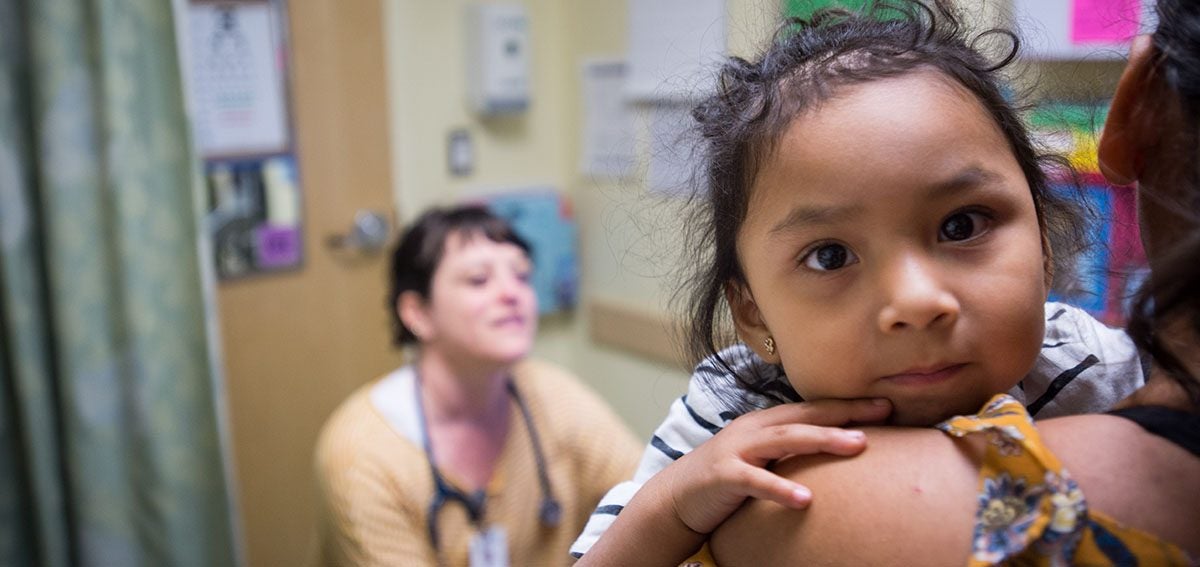 Mother and baby at clinic with doctor. Baby is looking directly into the camera.