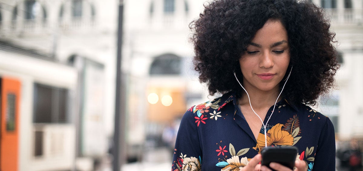 young woman listening to her phone through headphones