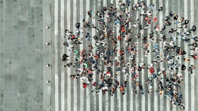 crowd of peoople make the shape of a speech bubble, photographed from above
