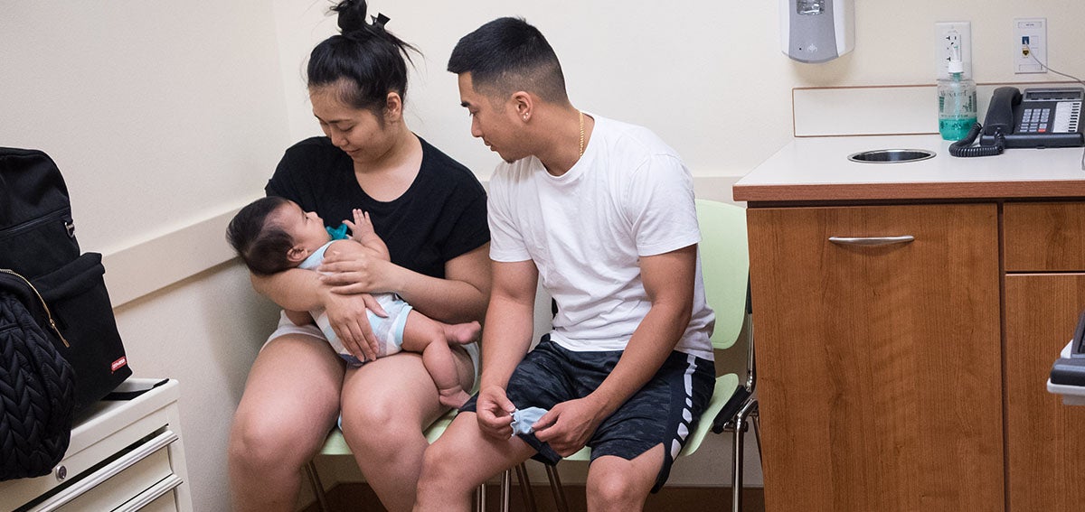 Parents with their infant at the in a safety net clinic exam room 