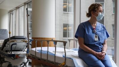 Doctor wearing surgical mask looks out of window.