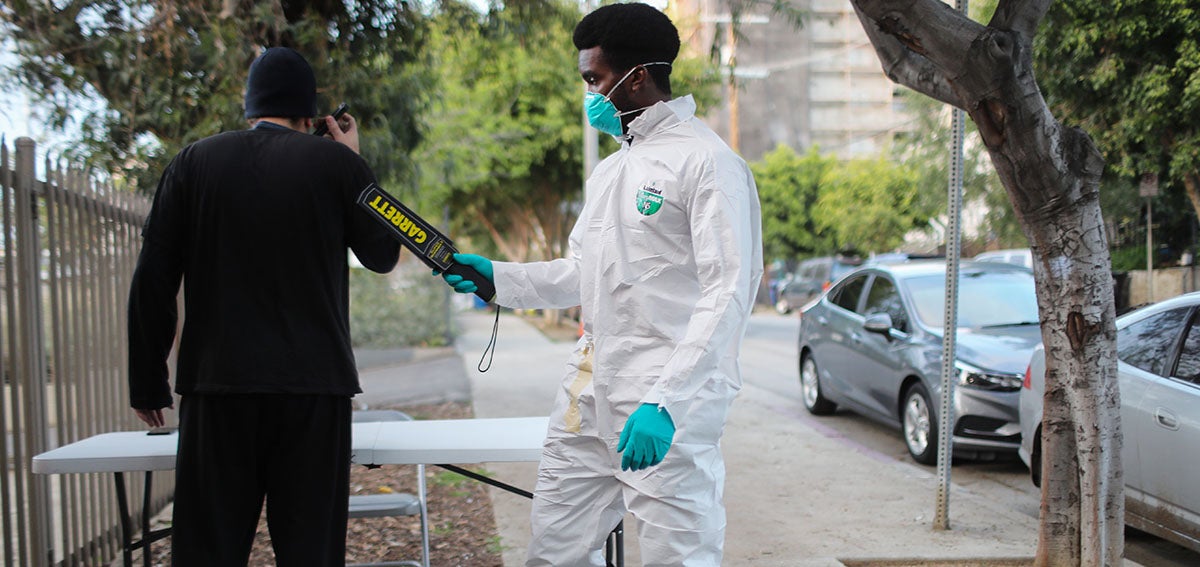 Security worker wearing mask, glove, and coveralls during COVID-19 outbreak.