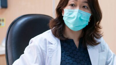 Physician wearing surgical mask, speaking to patient in exam room