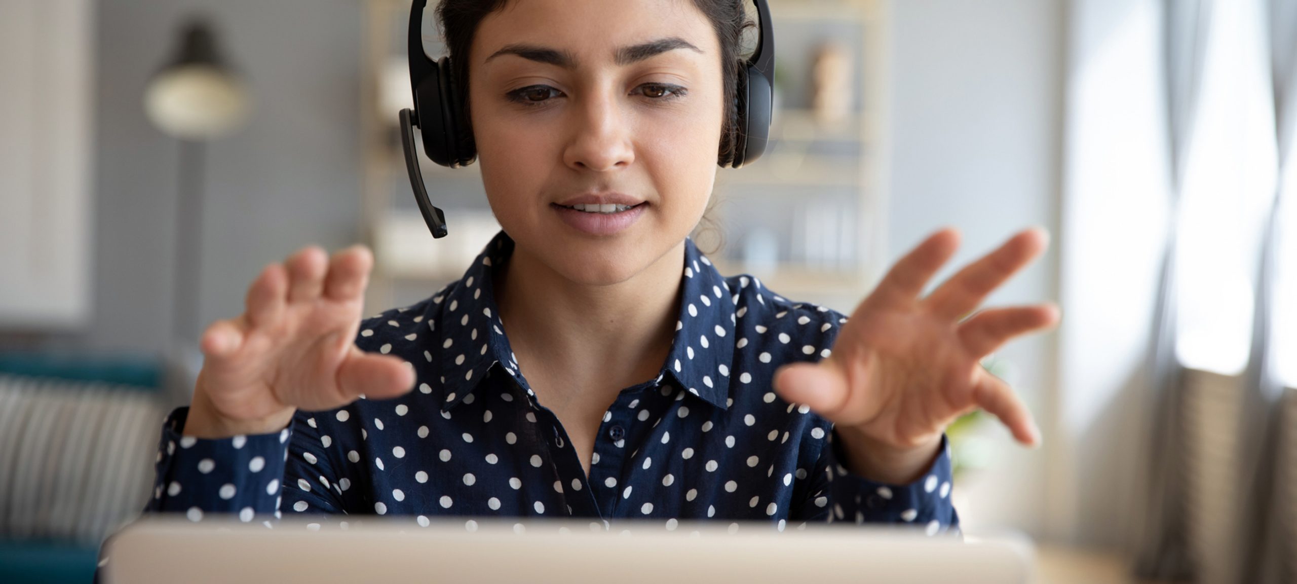 Woman wears wireless headset on video conference call on her laptop