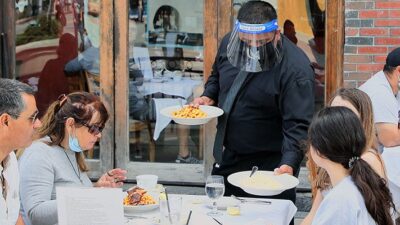 Waiter serves meal to customers wearing PPE