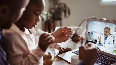 Father and child talk to doctor on a laptop