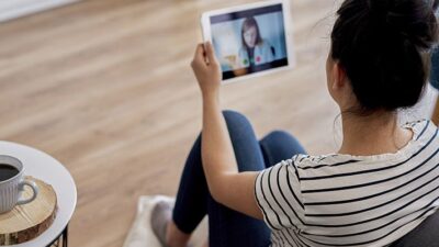 Woman talks to doctor by video conference, using an iPad