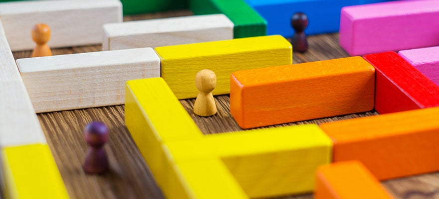 wood game pieces in a maze made of toy blocks