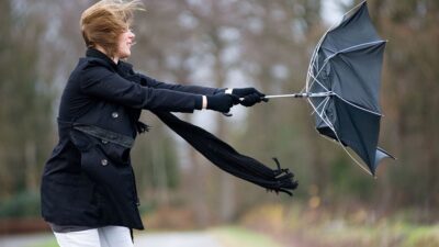 woman trying to hold on to umbrela that is blowing away