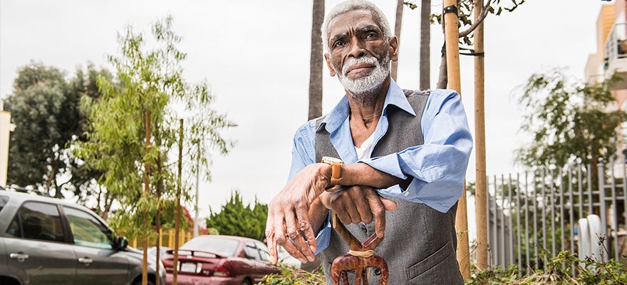 Chris Austin sits outside resting his arms on elaborately carved cane