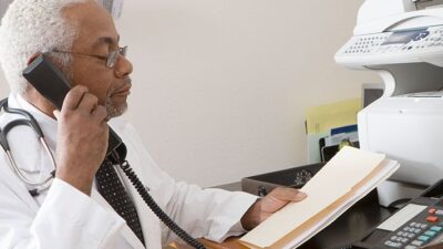 Doctor speaking on phone, holding file folder.