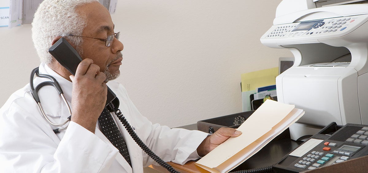 Doctor speaking on phone, holding file folder.