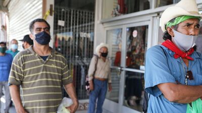 men waiting in line wearing cloth masks