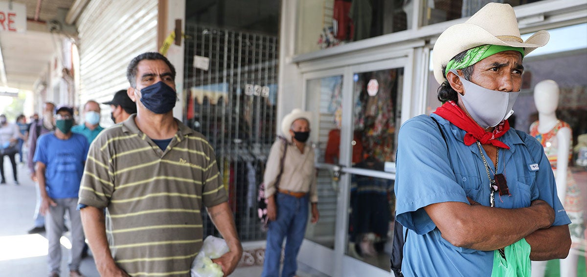 men waiting in line wearing cloth masks