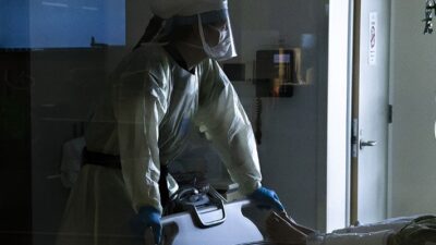 A nurse wearing a powered air-purifying respirator checks on a patients vital signs inside a Covid-19 intensive care unit.