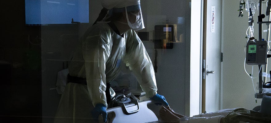A nurse wearing a powered air-purifying respirator checks on a patients vital signs inside a Covid-19 intensive care unit.