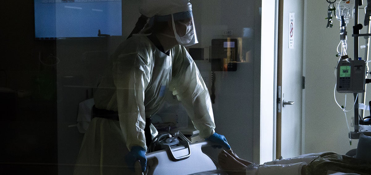 A nurse wearing a powered air-purifying respirator checks on a patients vital signs inside a Covid-19 intensive care unit.