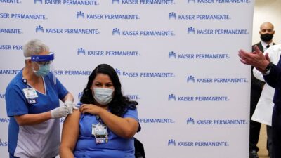 California's Governor Gavin Newsom looks on as ICU nurse Helen Cordova receives vaccine