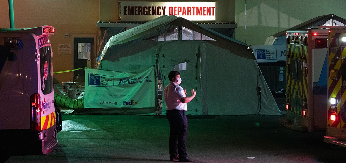 An emergency medical technician (EMT) directs an ambulance outside the emergency room