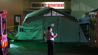 An emergency medical technician (EMT) directs an ambulance outside the emergency room